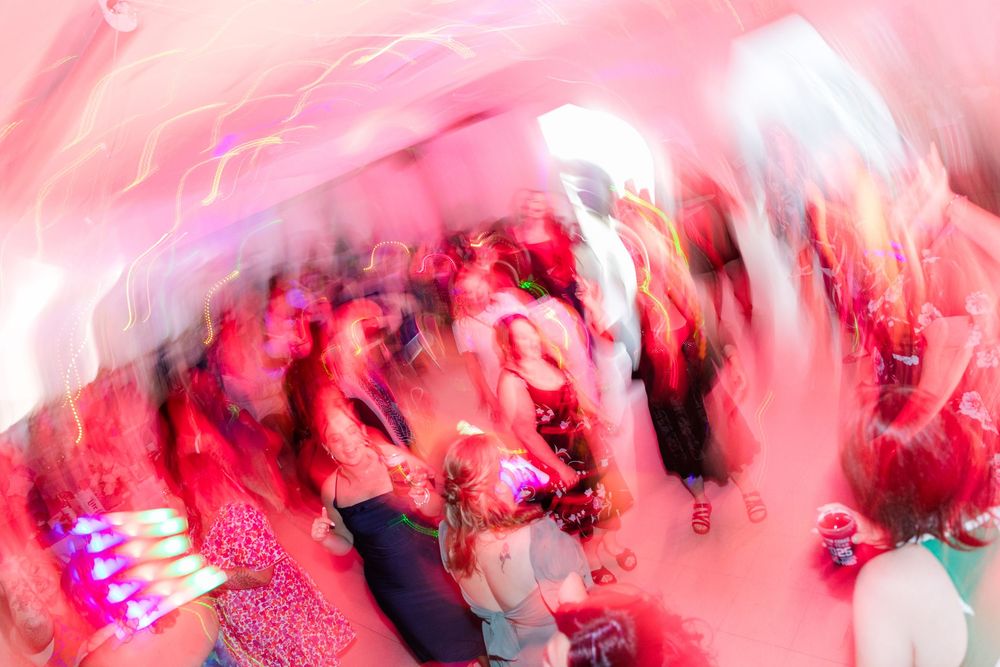 Abstract motion-blurred photograph of dancers in pink and red lighting creates an artistic party atmosphere.