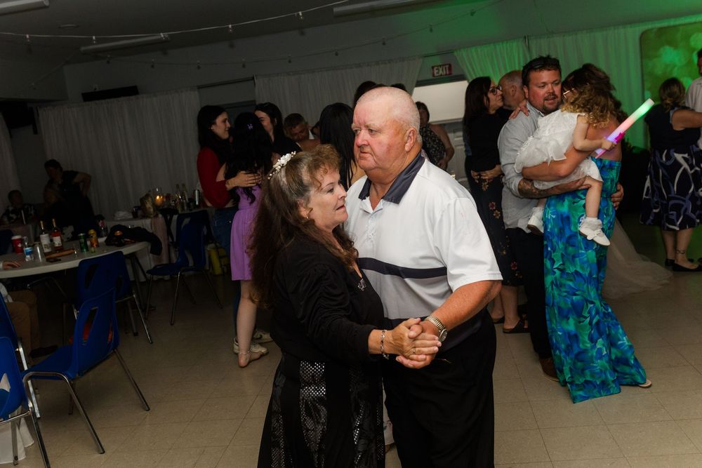 Couples dancing together at an indoor social event with atmospheric lighting.