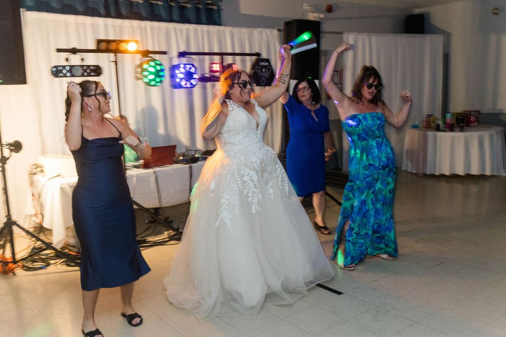 People dancing at a wedding reception with someone in a white gown celebrating on the dance floor.