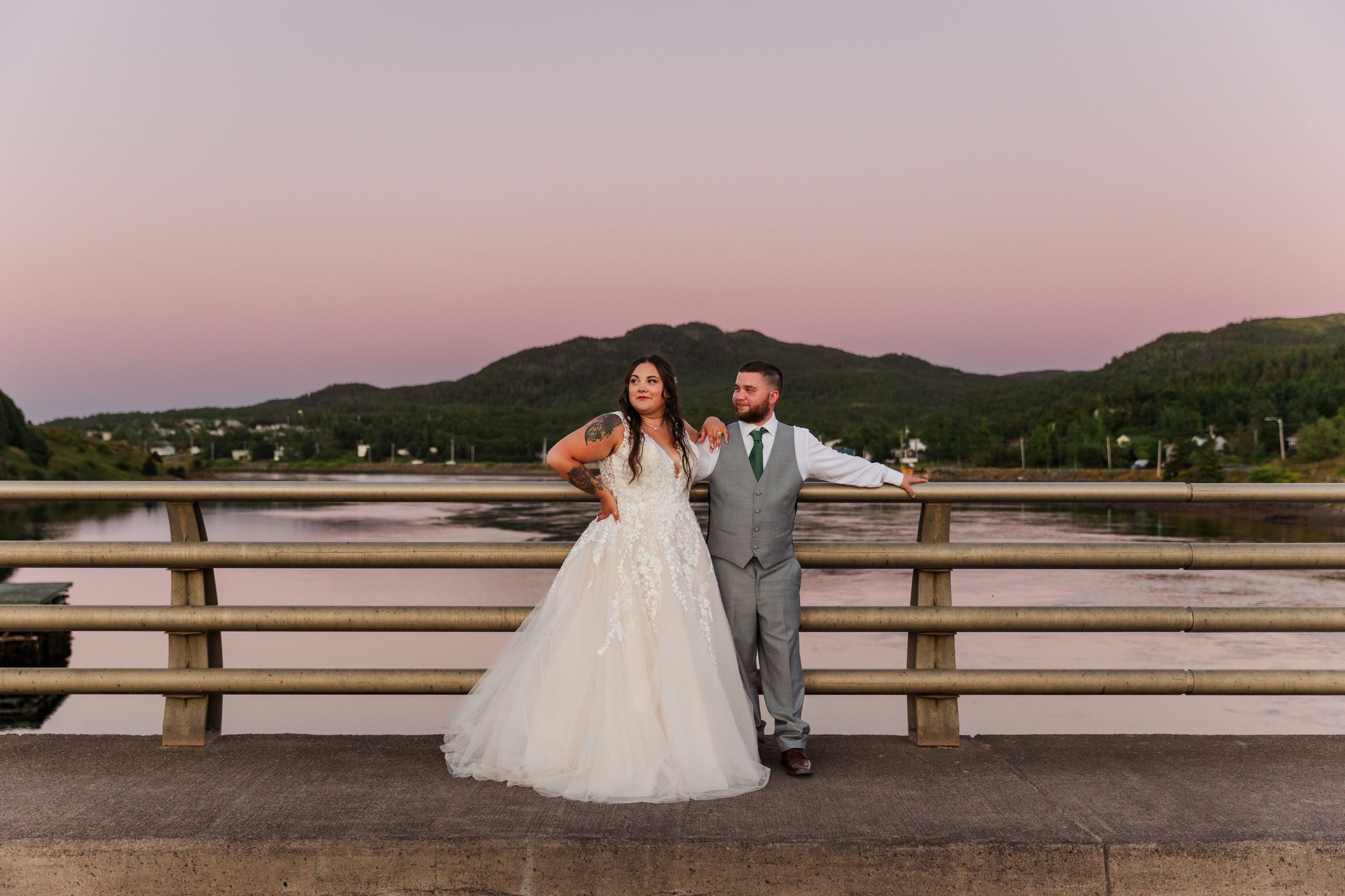 A beautiful sunset wedding photo session with a couple posing by a rustic waterfront dock and wooden railing.