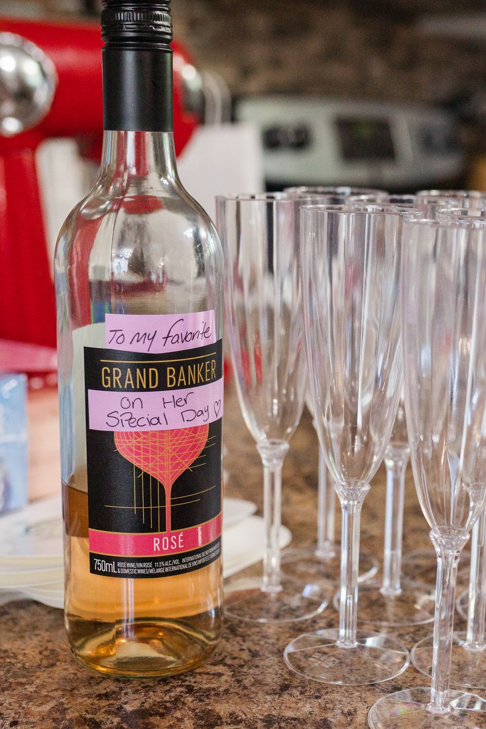 A bottle of Grand Banco special day liquor sits beside empty champagne flutes on a countertop.