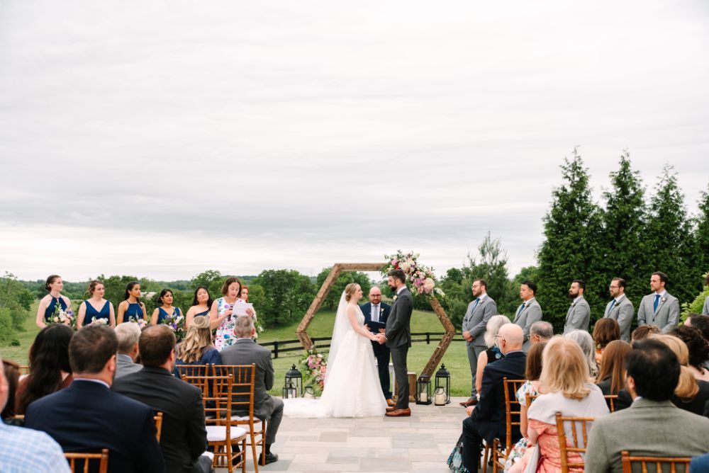 Wedding guests seated outdoors at a rustic venue with mountain views in the background.