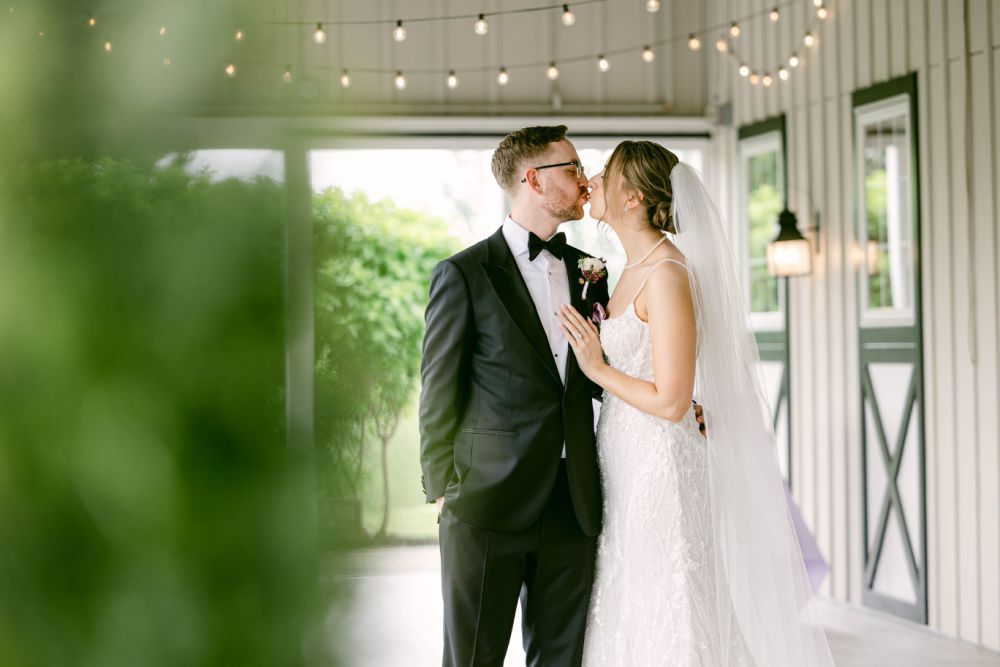 Romantic bride and groom share intimate moments in a bright covered walkway with natural lighting.