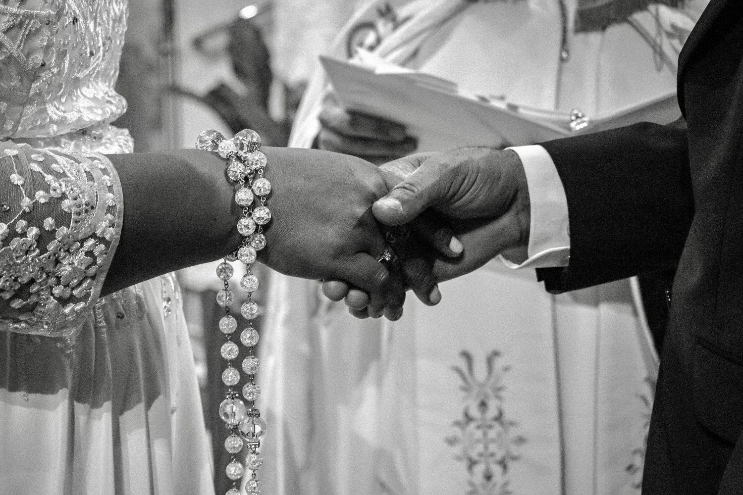 Black and white wedding ring exchange sequence showing hands joining together in ceremony.