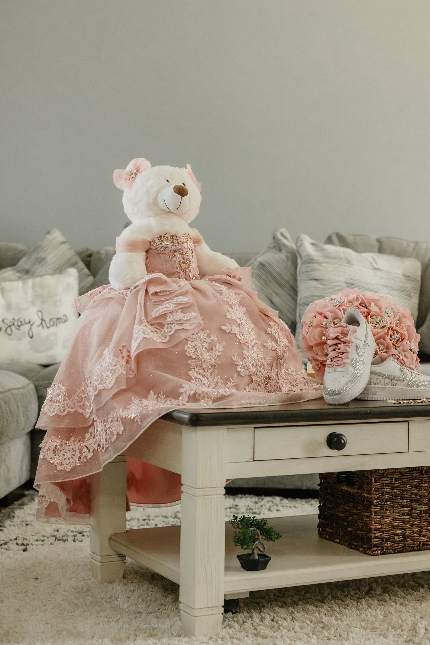 Elegant pink lace gown with delicate details draped over a white bench with rustic decor.