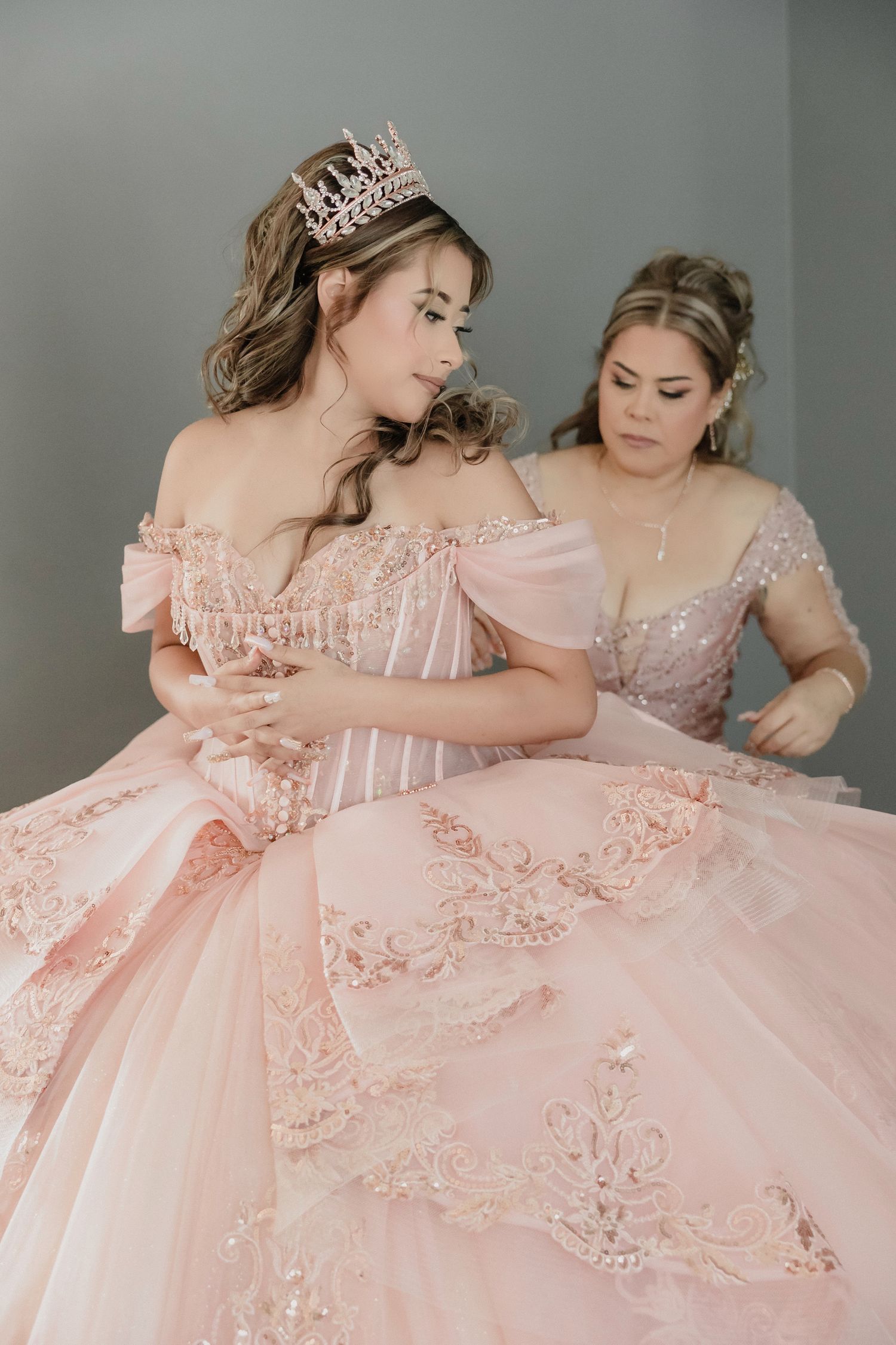 Two elegant pink ballgowns with intricate embroidery details and delicate ruffles shown in intimate close-up shots.