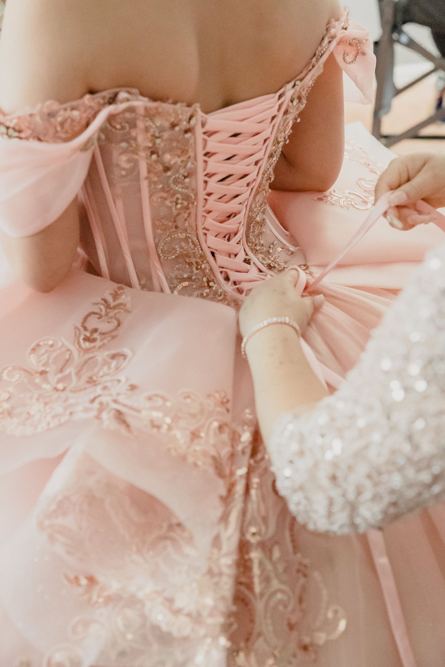 Close-up details of a delicate pink lace corset dress with intricate beading and ribbon embellishments.