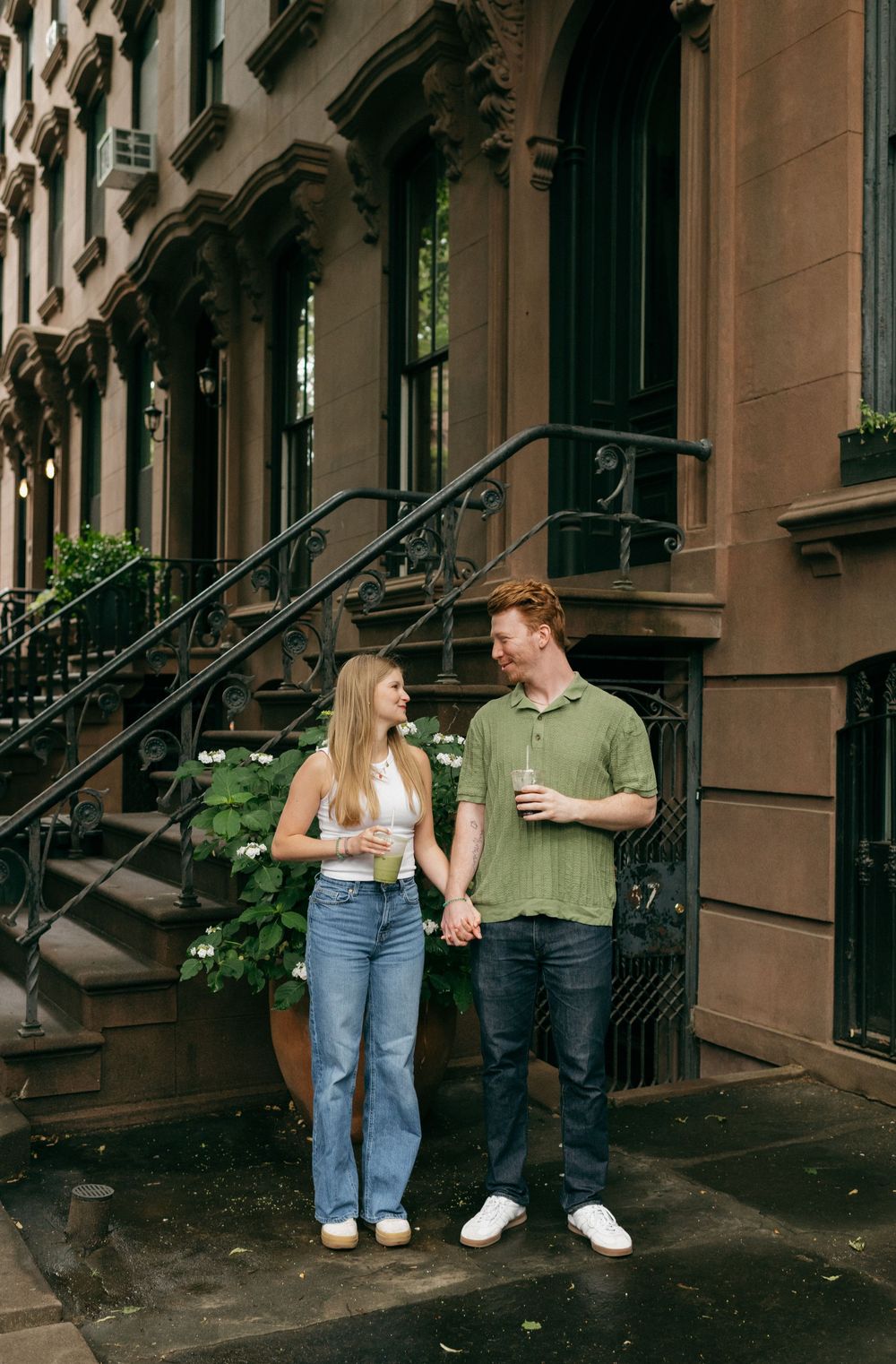 A couple sharing intimate moments on brownstone steps in an urban setting.