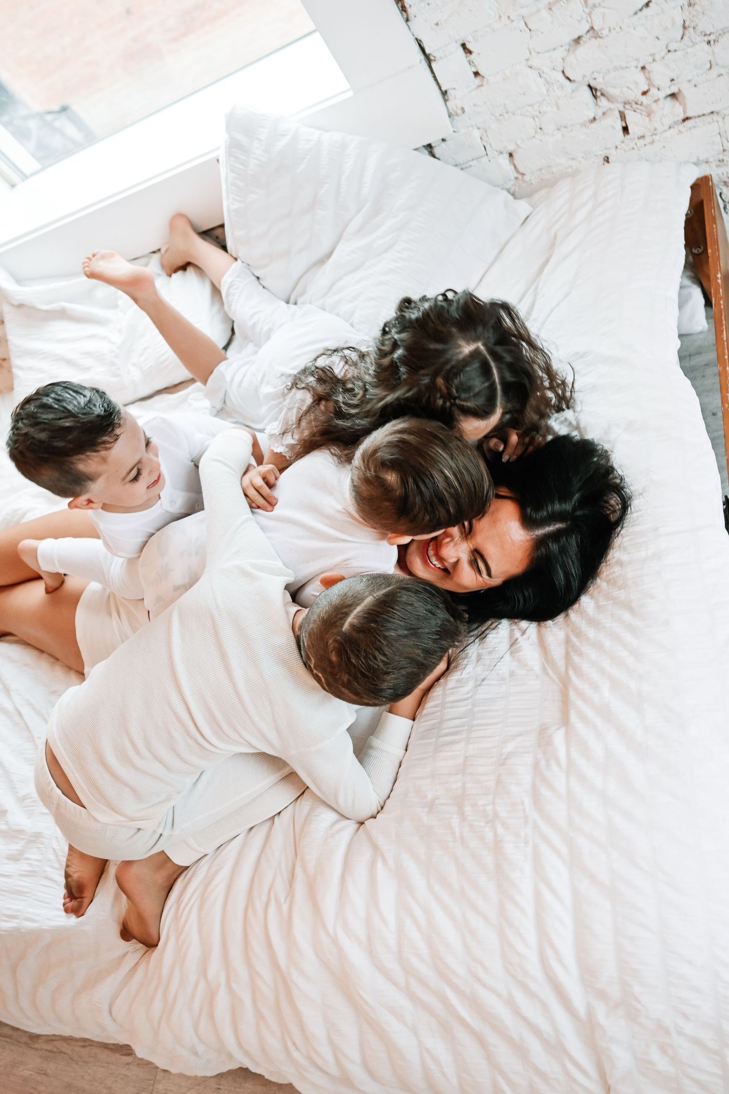 A couple lying on white bedding sharing playful and intimate moments together.