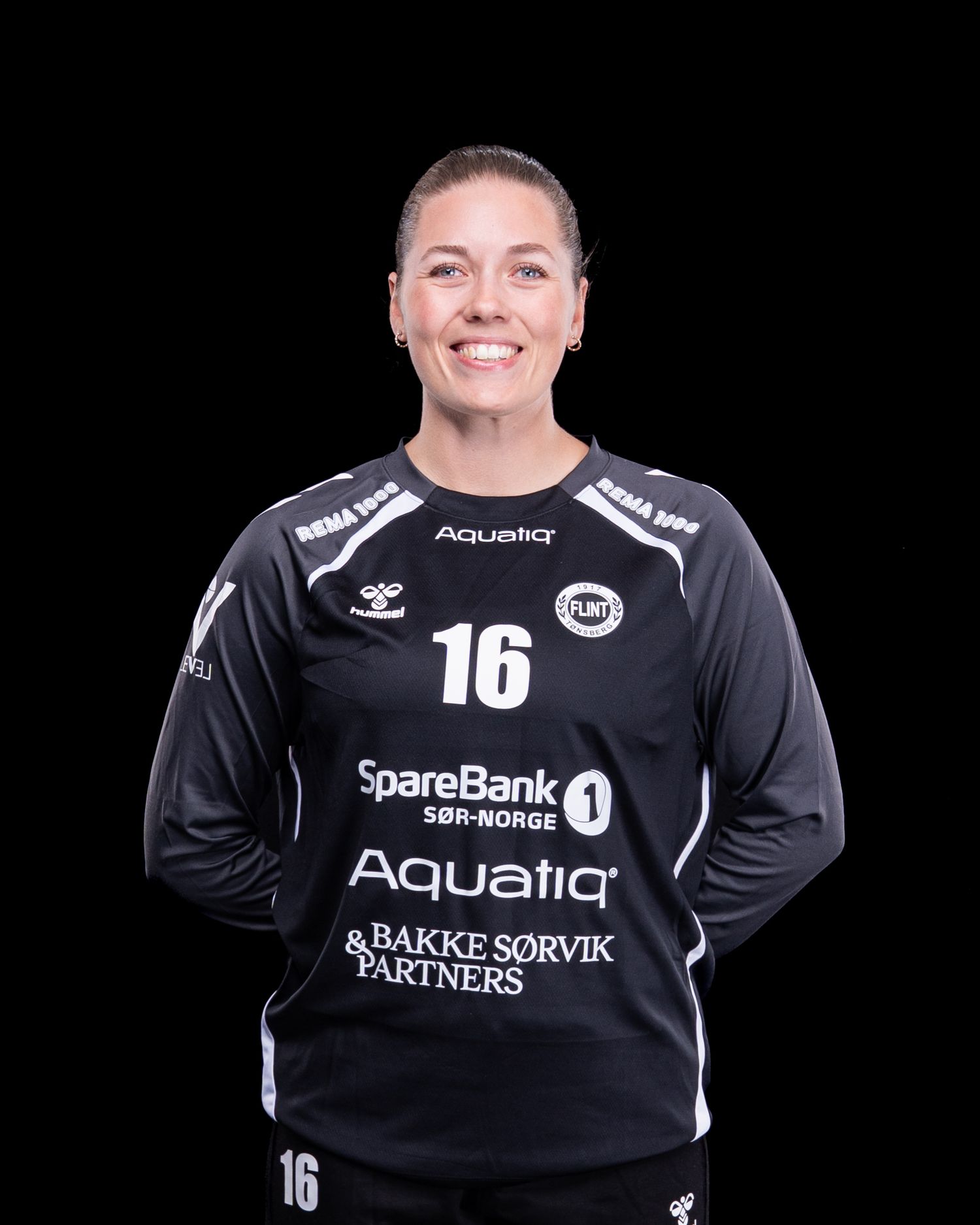 Professional sports portrait photo of a handball goalkeeper wearing black jersey with number 16 and sports equipment.