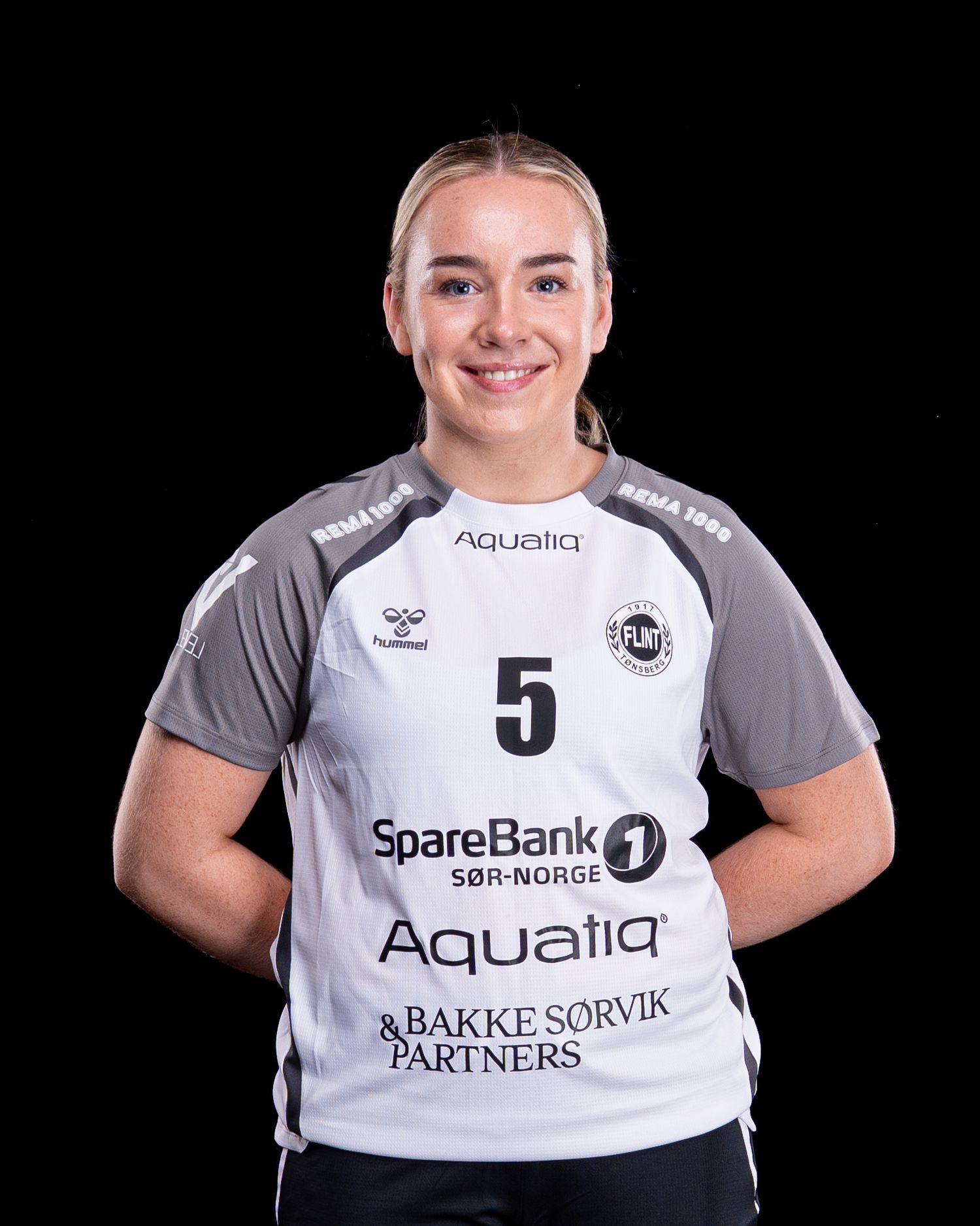 Professional sports team members pose in white and gray uniforms with sponsor logos Aqualia and SpareBank1 visible.