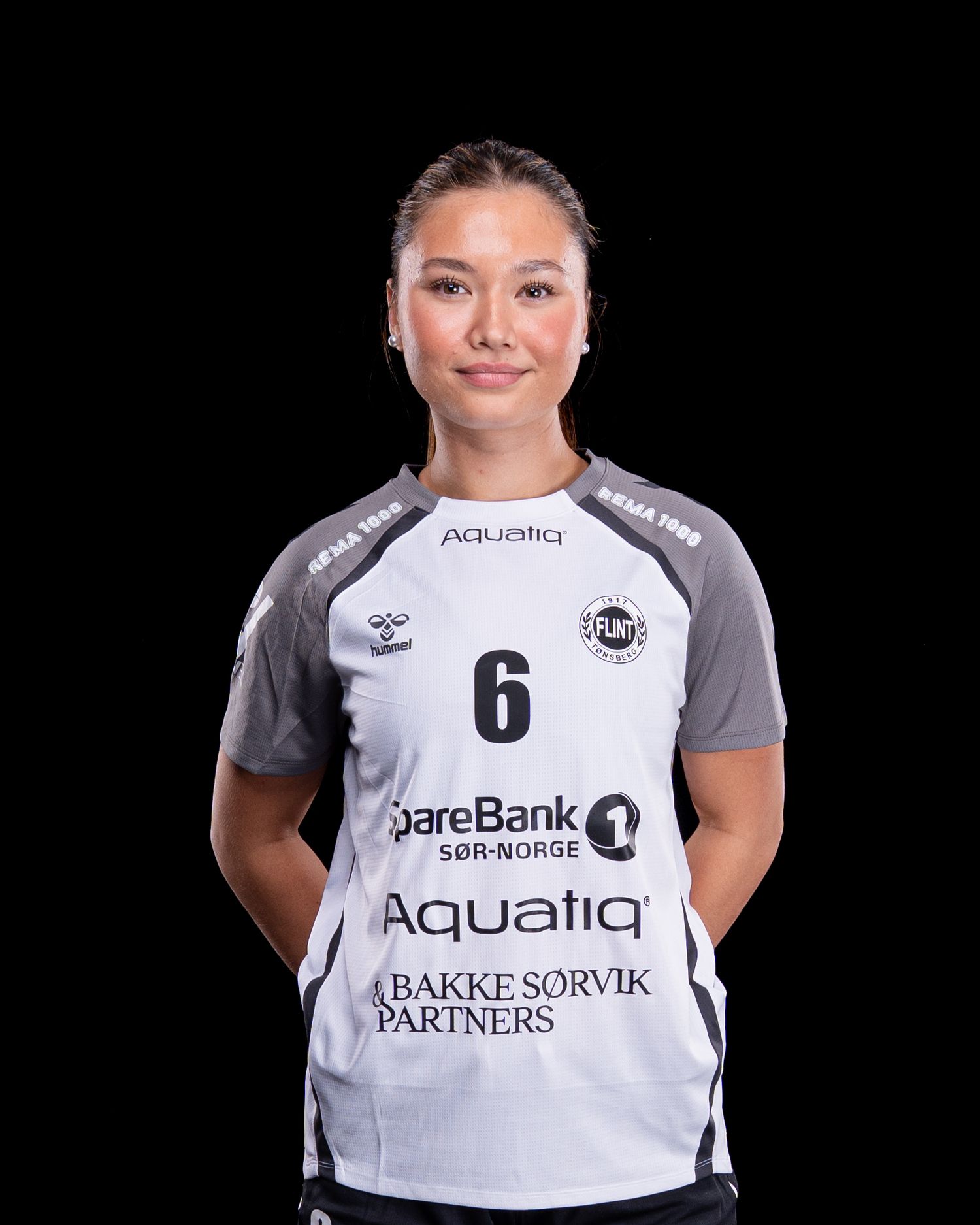Athletic player wearing white jersey with number 6 and SpareBank sponsor logo stands against dark background.