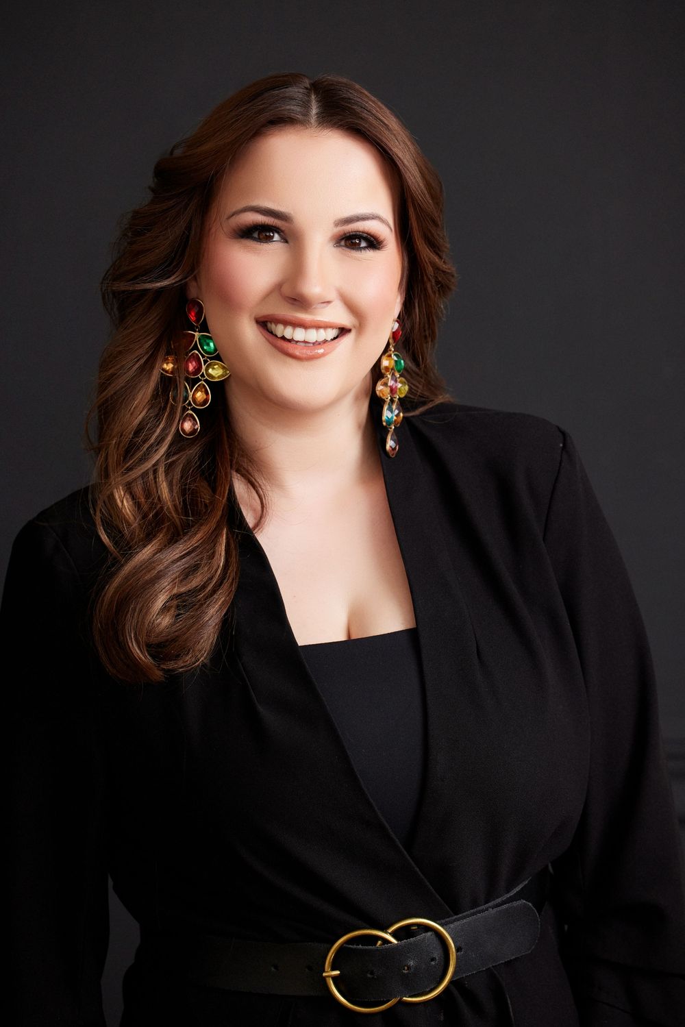 Fashion portraits featuring elegant black blazer and statement earrings against dark backdrop.