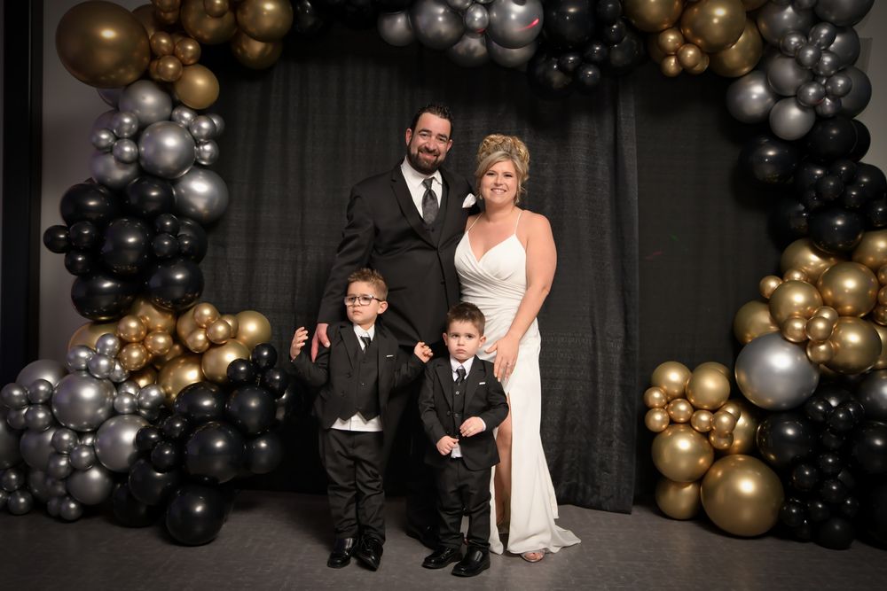 Wedding ceremony decor featuring elegant black and gold balloon arrangements against a dark backdrop.
