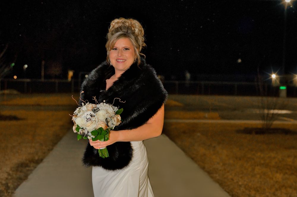 A bride and groom share a romantic nighttime moment outdoors with glowing lights in the background.