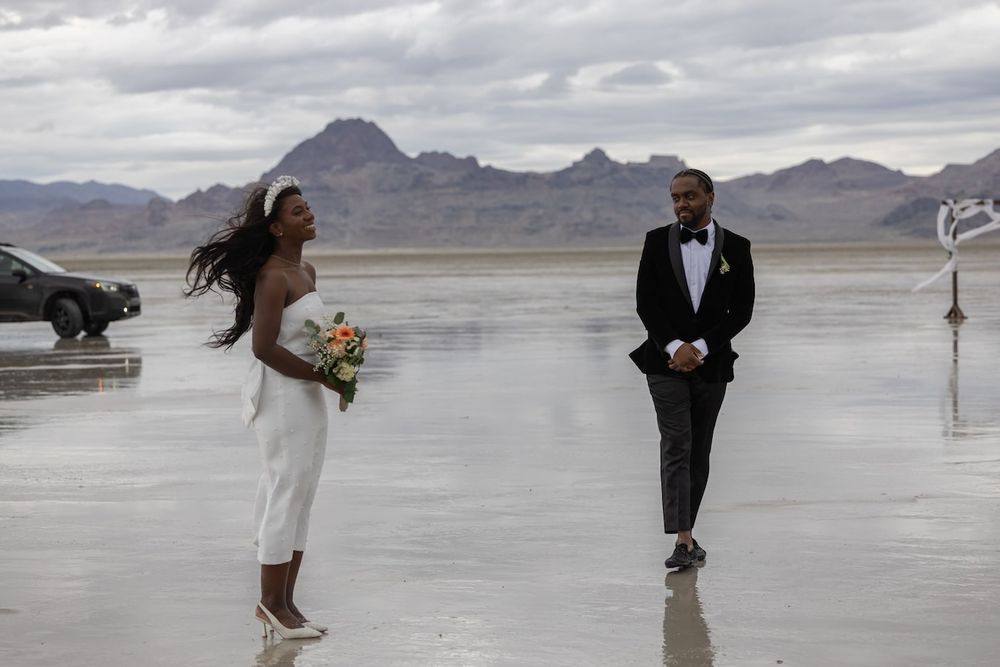 A couple poses for romantic wedding photos on the scenic Bonneville Salt Flats in Utah under cloudy skies.