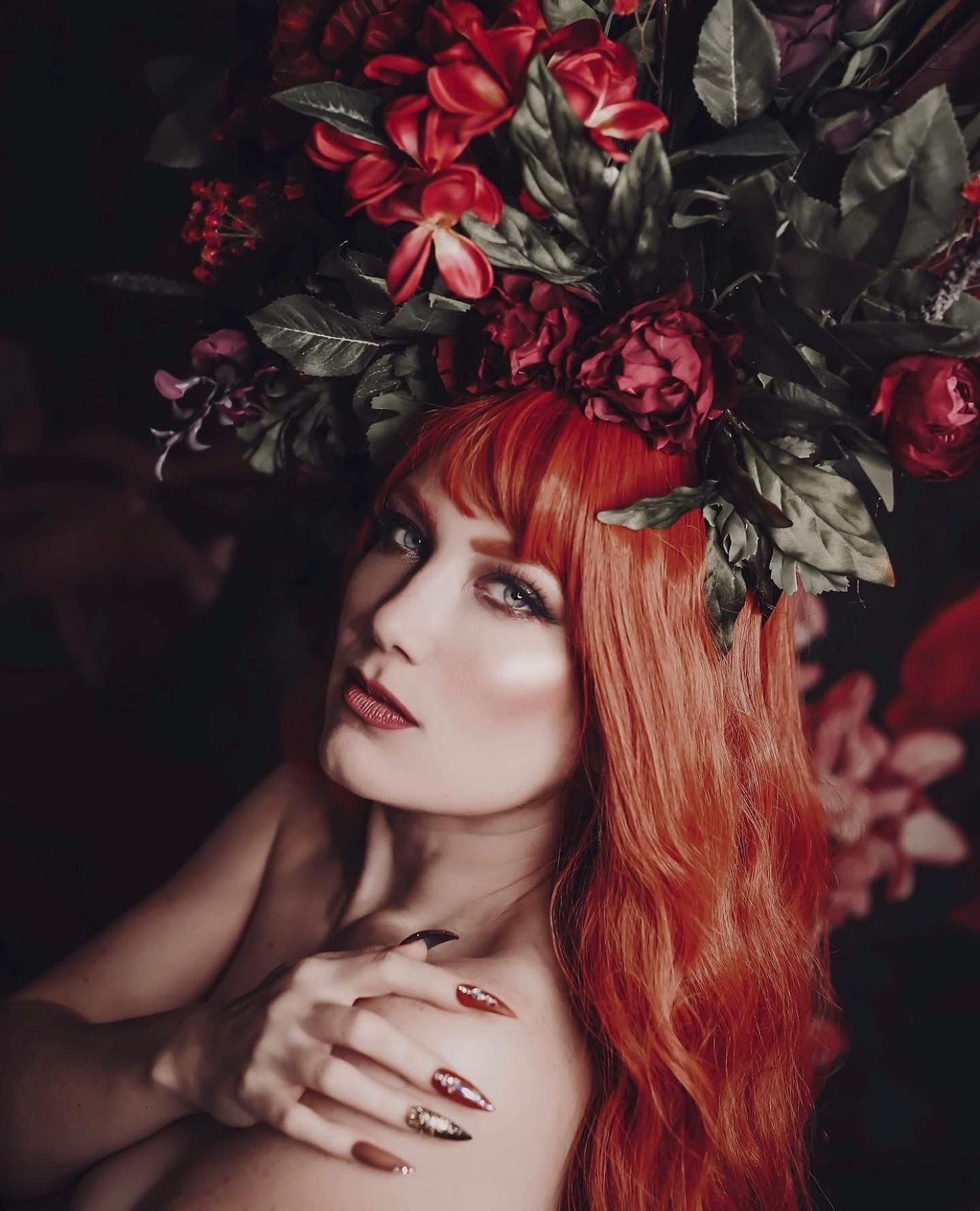 Artistic portrait featuring red roses and dark foliage creating a dramatic romantic mood.