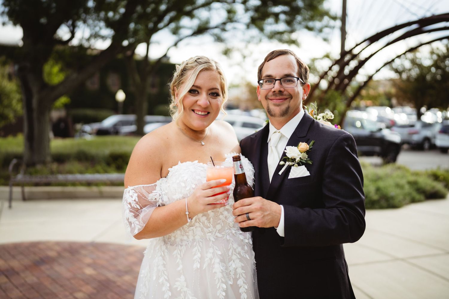 A couple in formal wedding attire shares a toast with colorful drinks on their special day.
