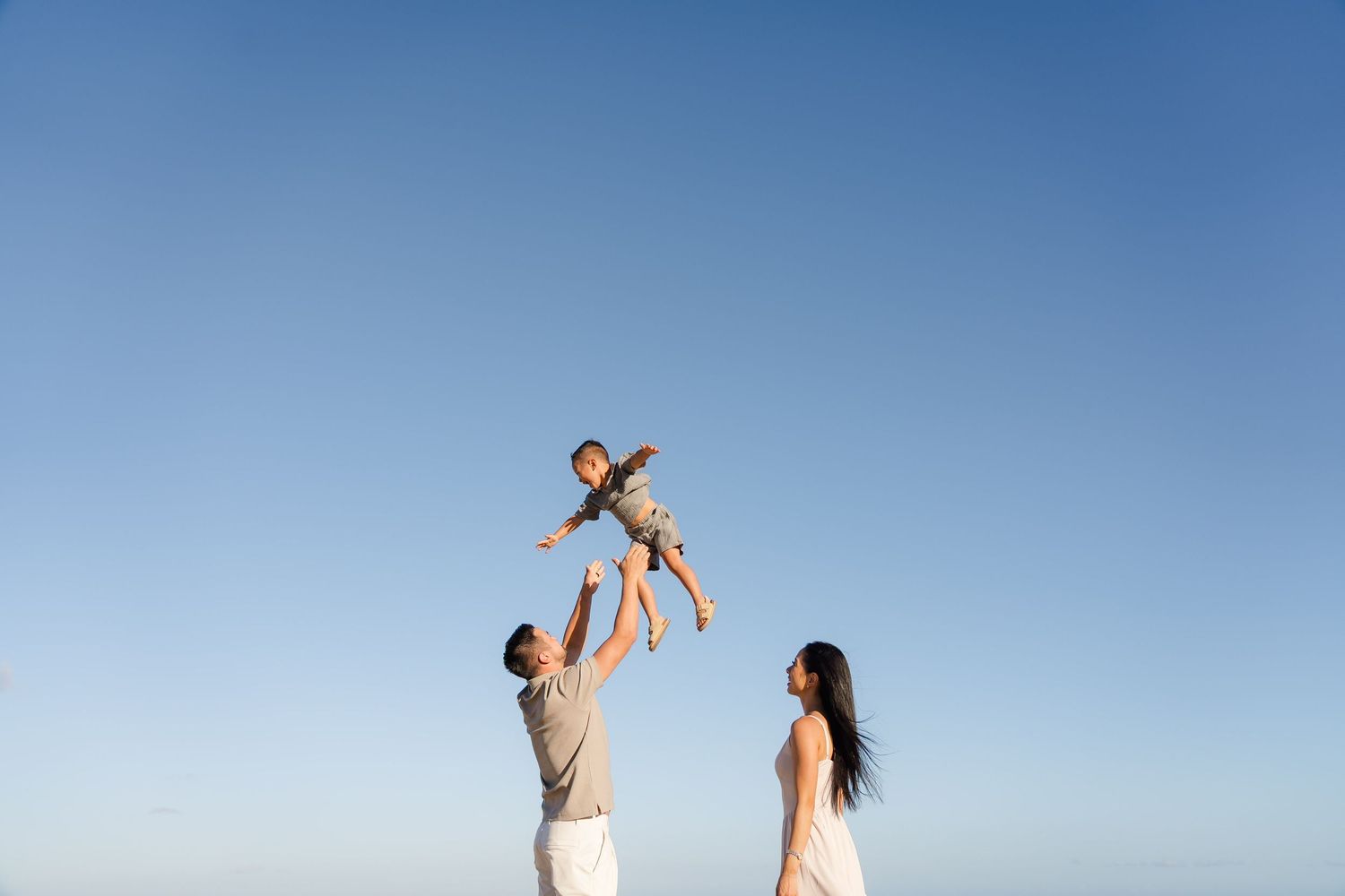 A group performs carefree dance poses in front of a bright blue sky background. Oahu family photography, Hawaii family photographer, natural