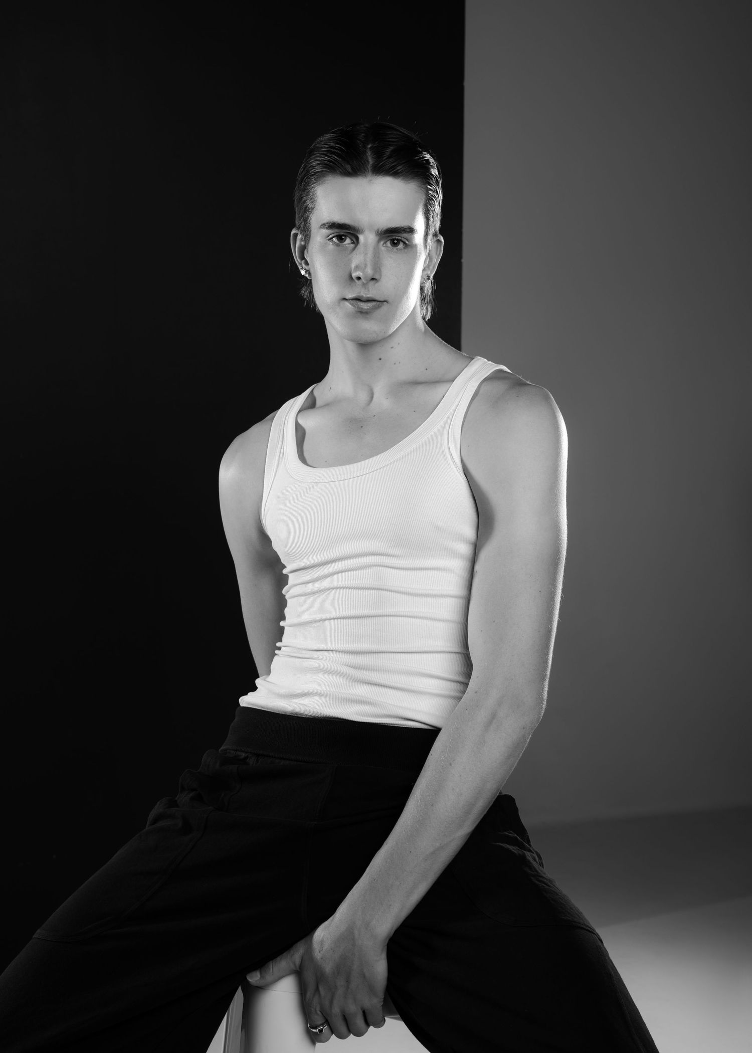 A black and white panoramic style photo series showing a person in a white tank top and dark pants against dark background.