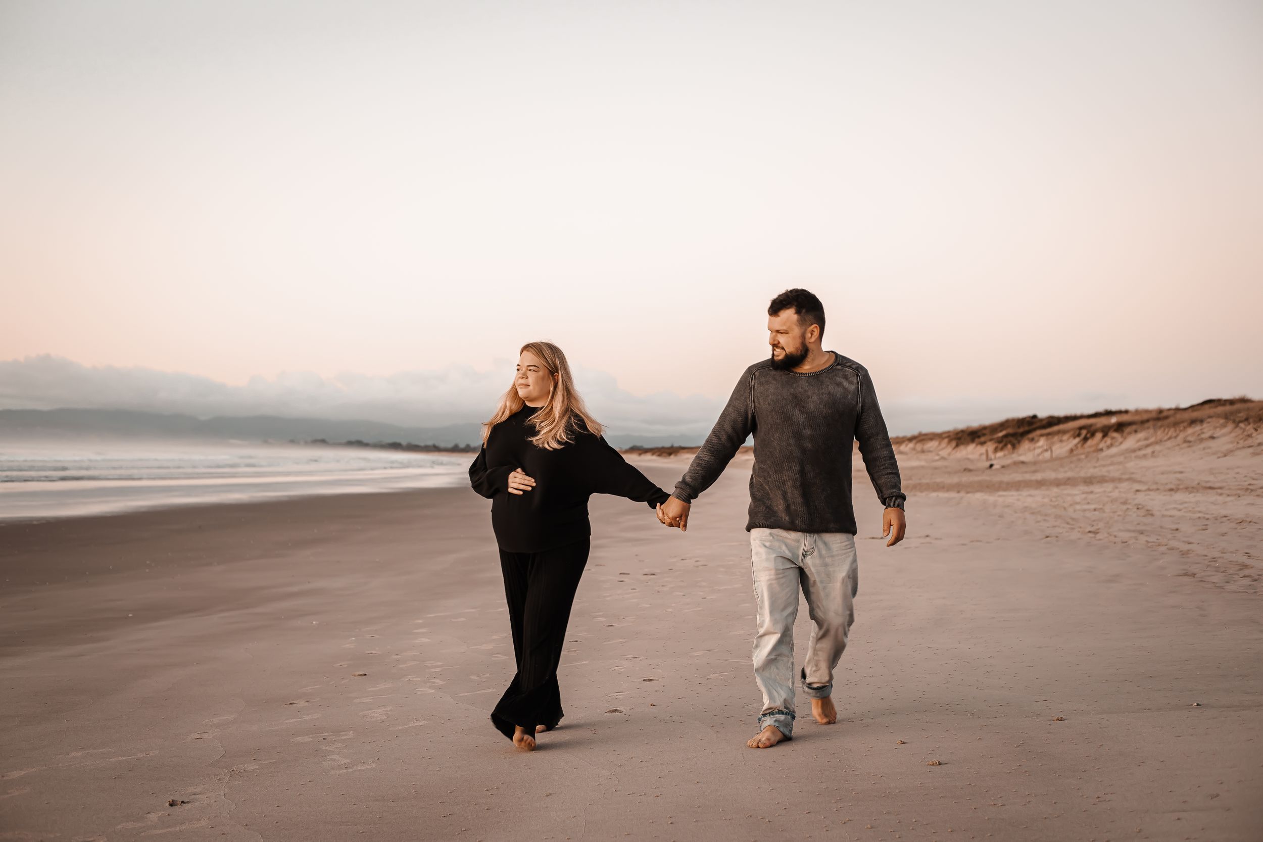 Holding hands Ruakaka couple walk along the beach