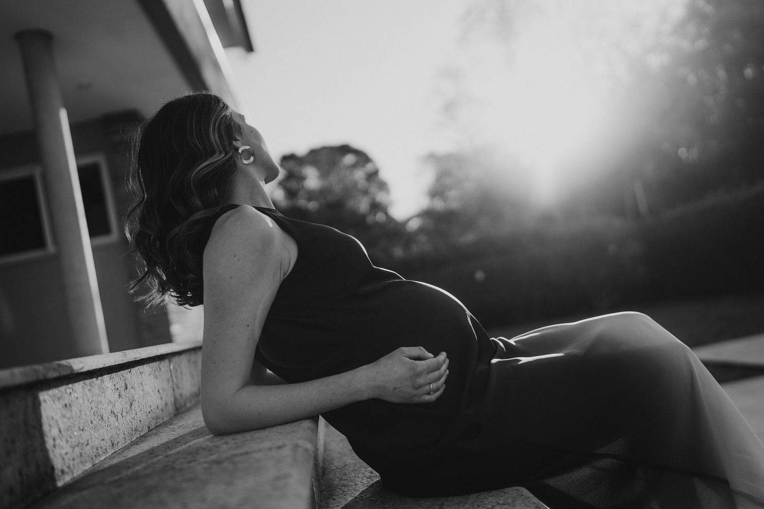 Black and white maternity portrait captured in relaxed outdoor setting at sunset.