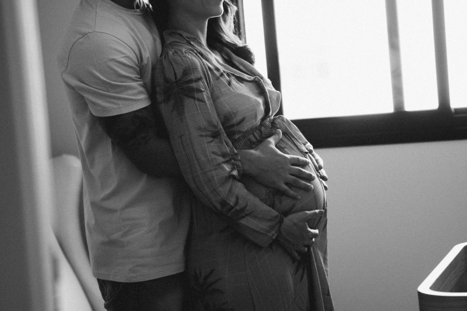 Intimate indoor photography session with natural window lighting and neutral tones.