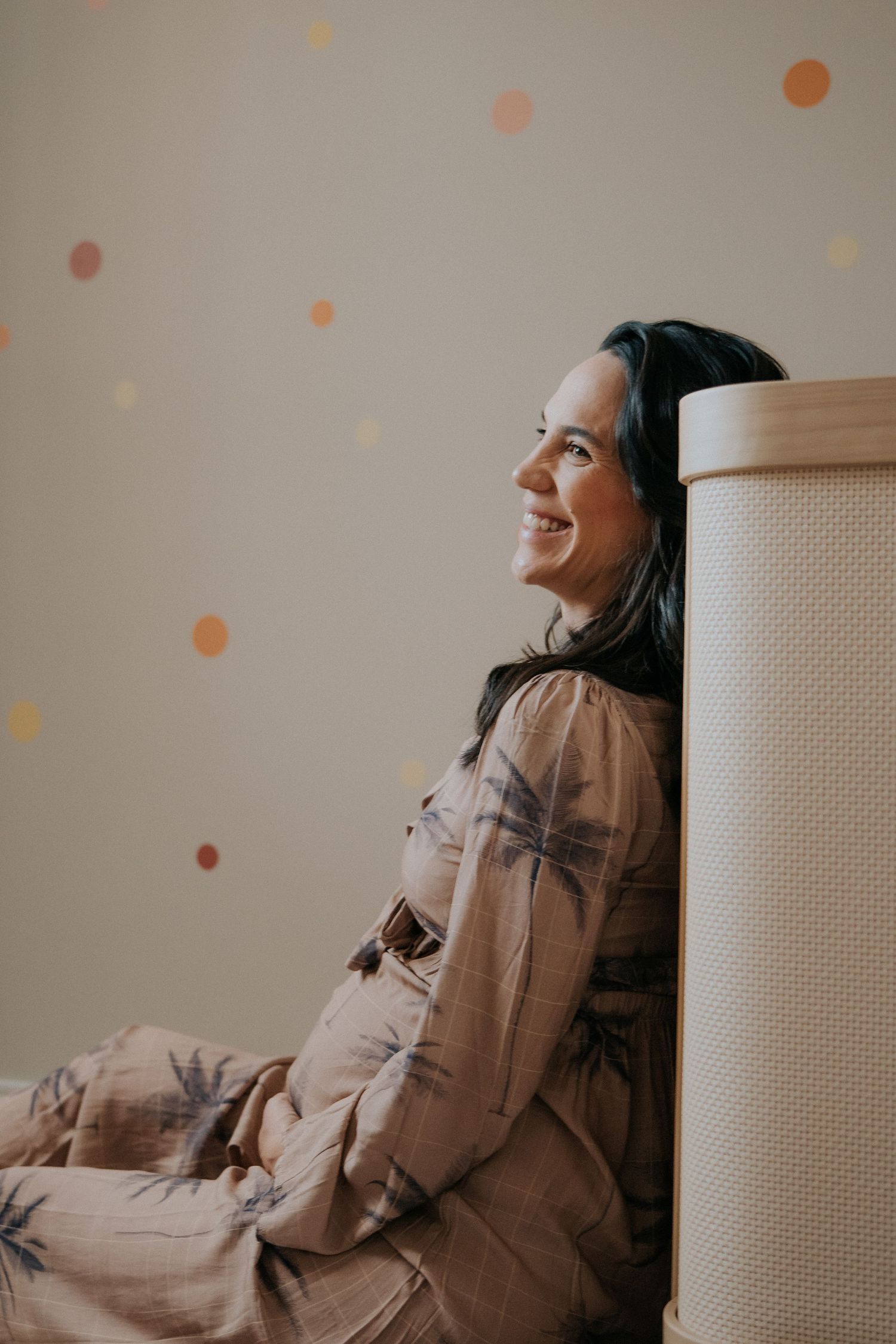 Lifestyle portrait session against a wall with soft peachy bokeh effects.