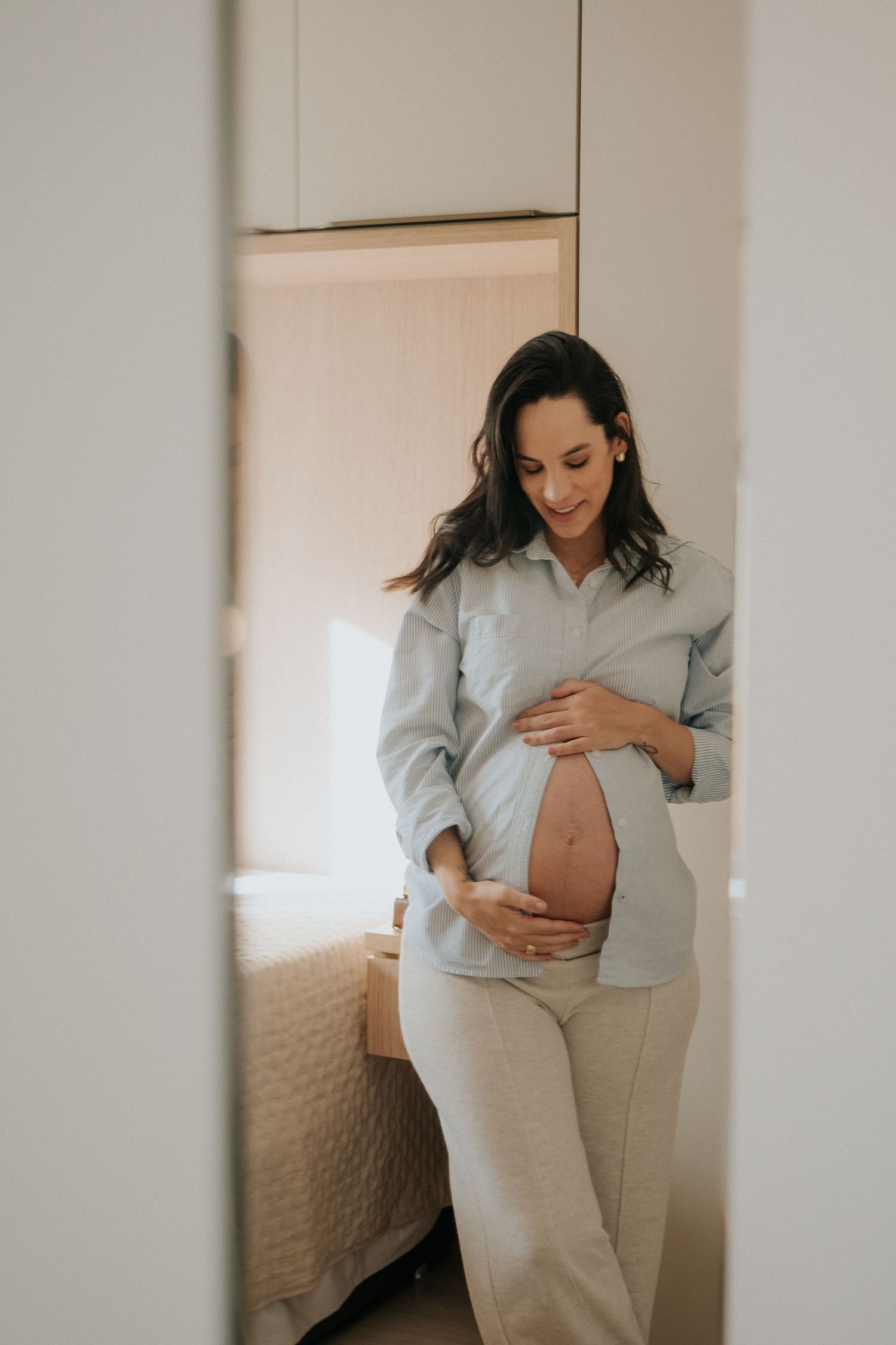 Maternity photography session in soft neutrals showing gentle belly touches.