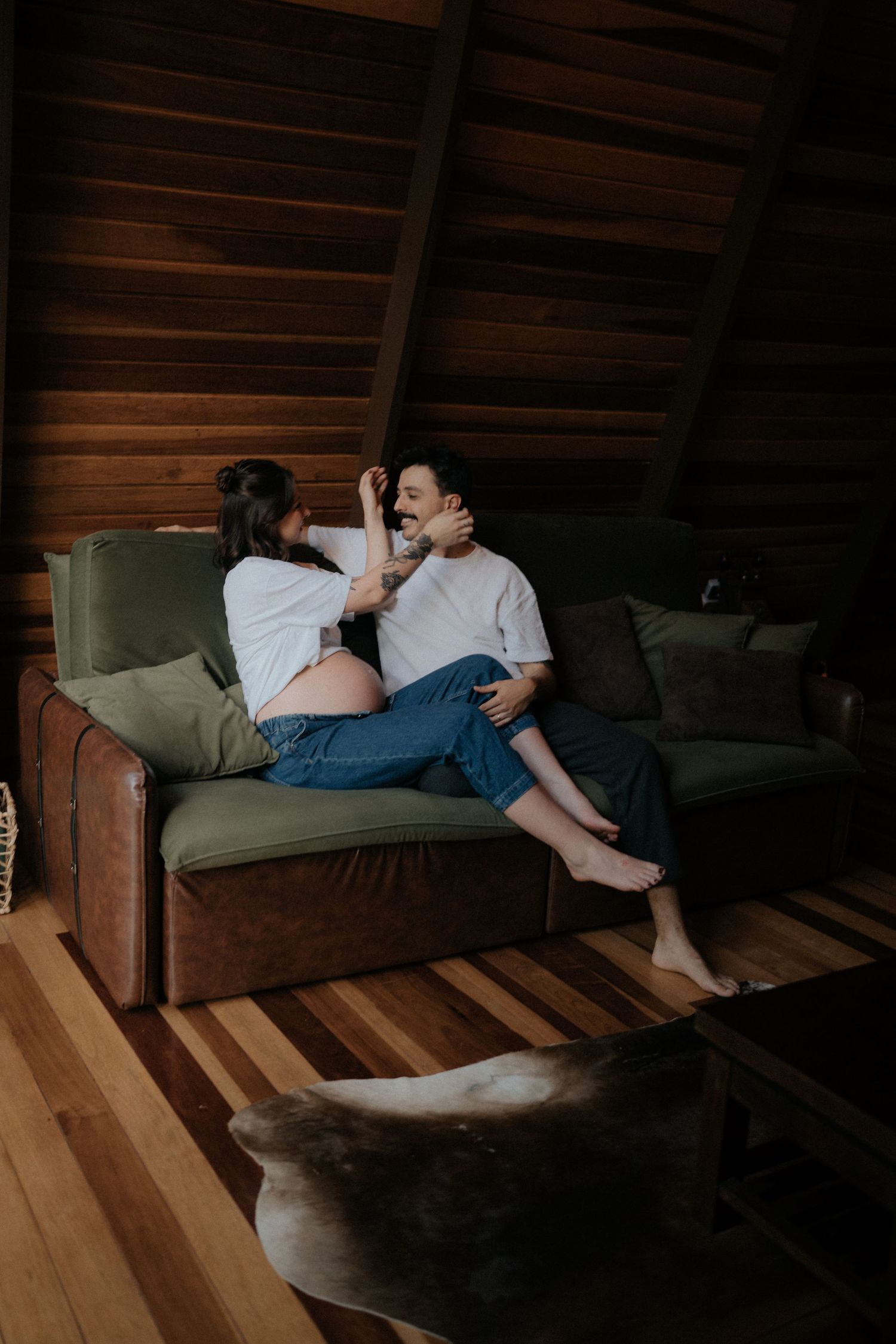 Intimate lifestyle moment on green couch in rustic cabin with wooden ceiling.