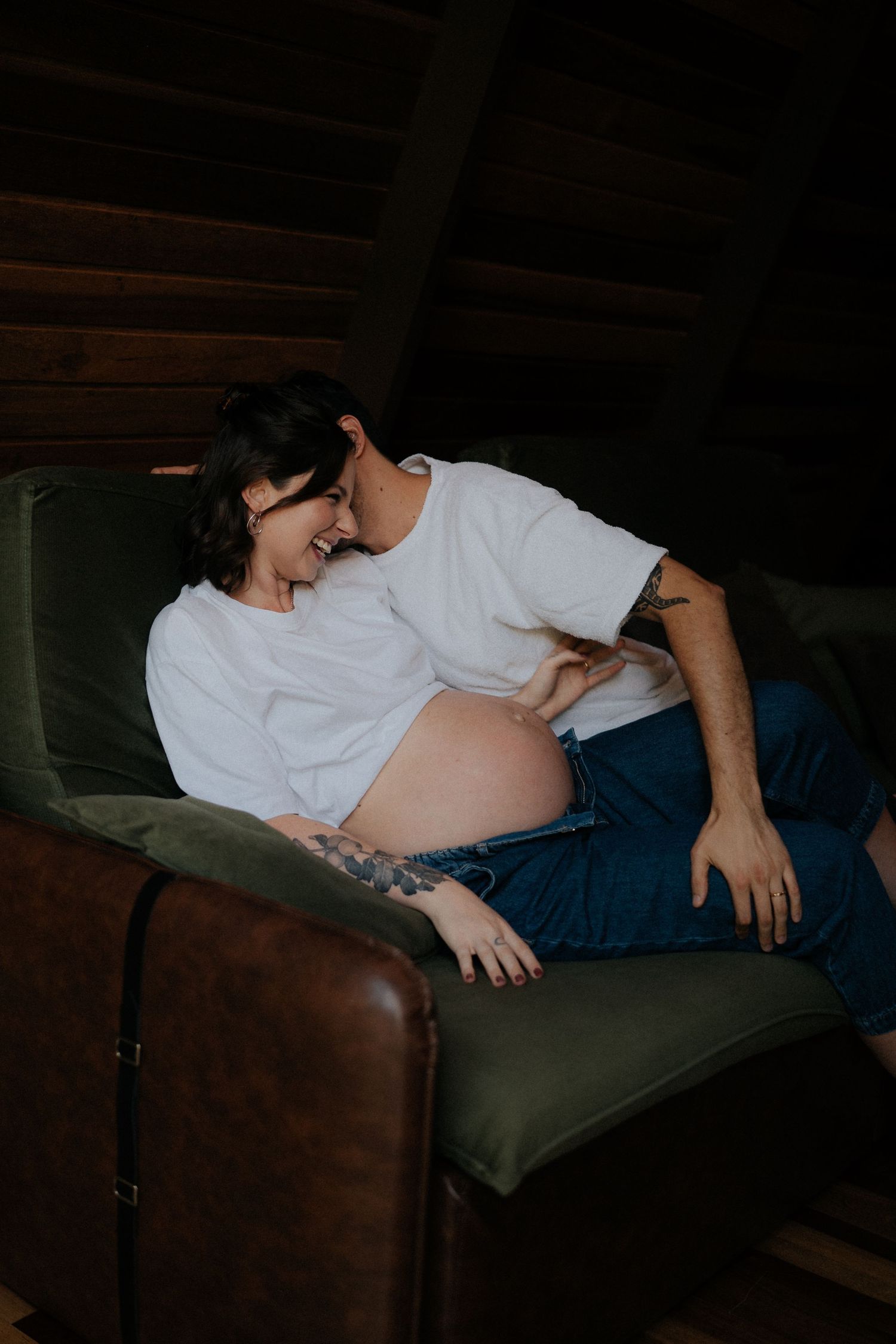 Candid moment shared on olive green couch in cozy indoor setting.