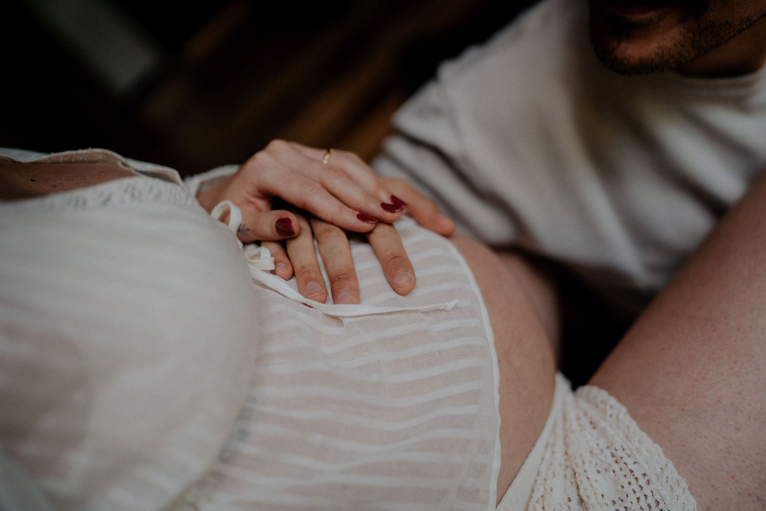 Close-up maternity photos showing delicate details in a white dress.