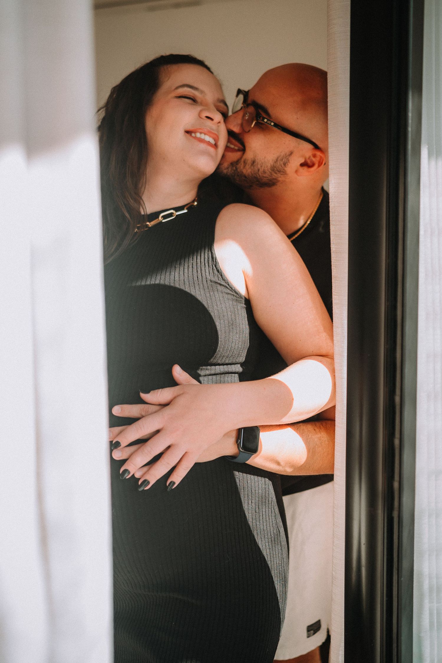 Intimate couple's portrait with tender embrace in natural window light.