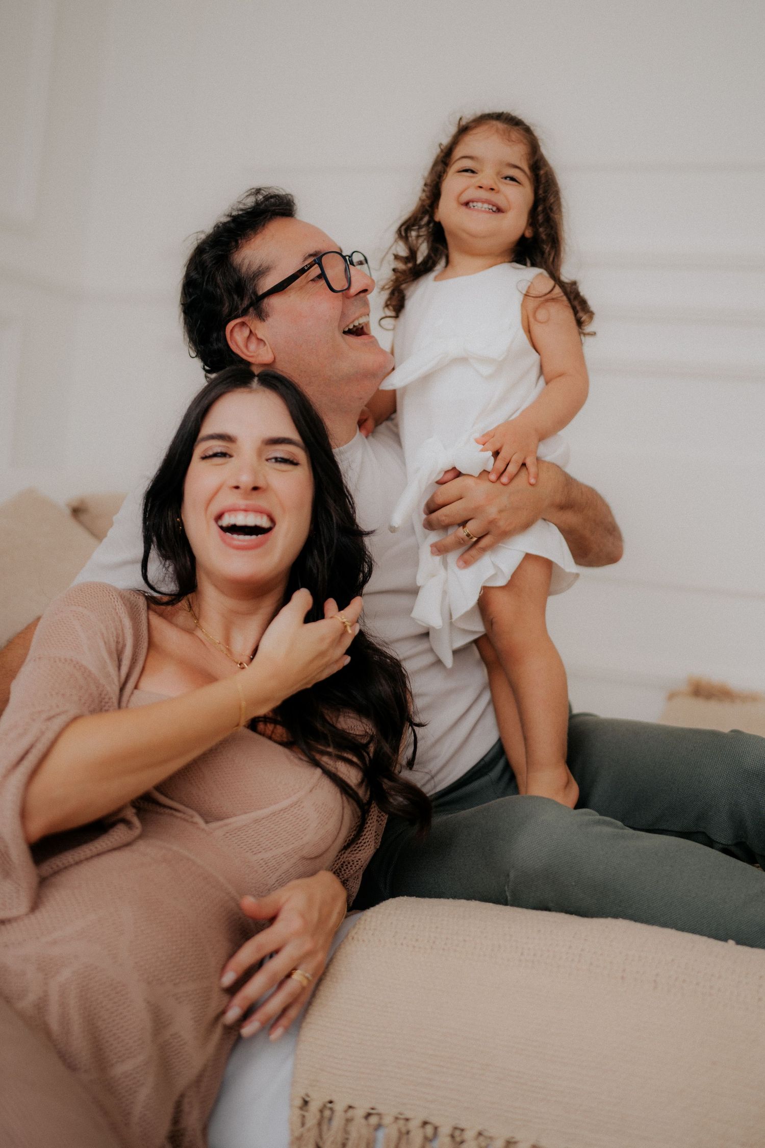 Family moment captured with joyful laughter on cozy beige couch.