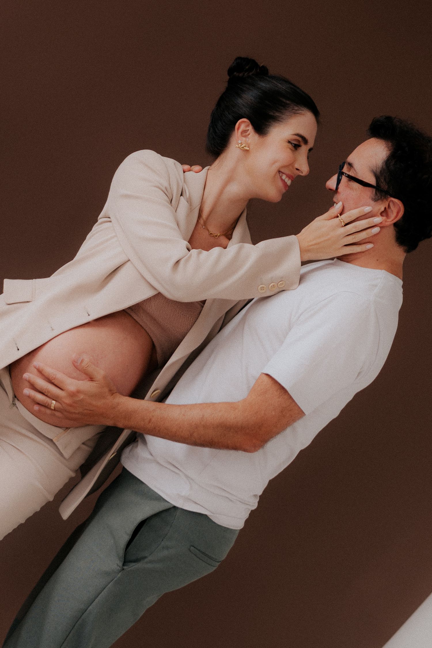 Couple embraces playfully in professional studio setting.