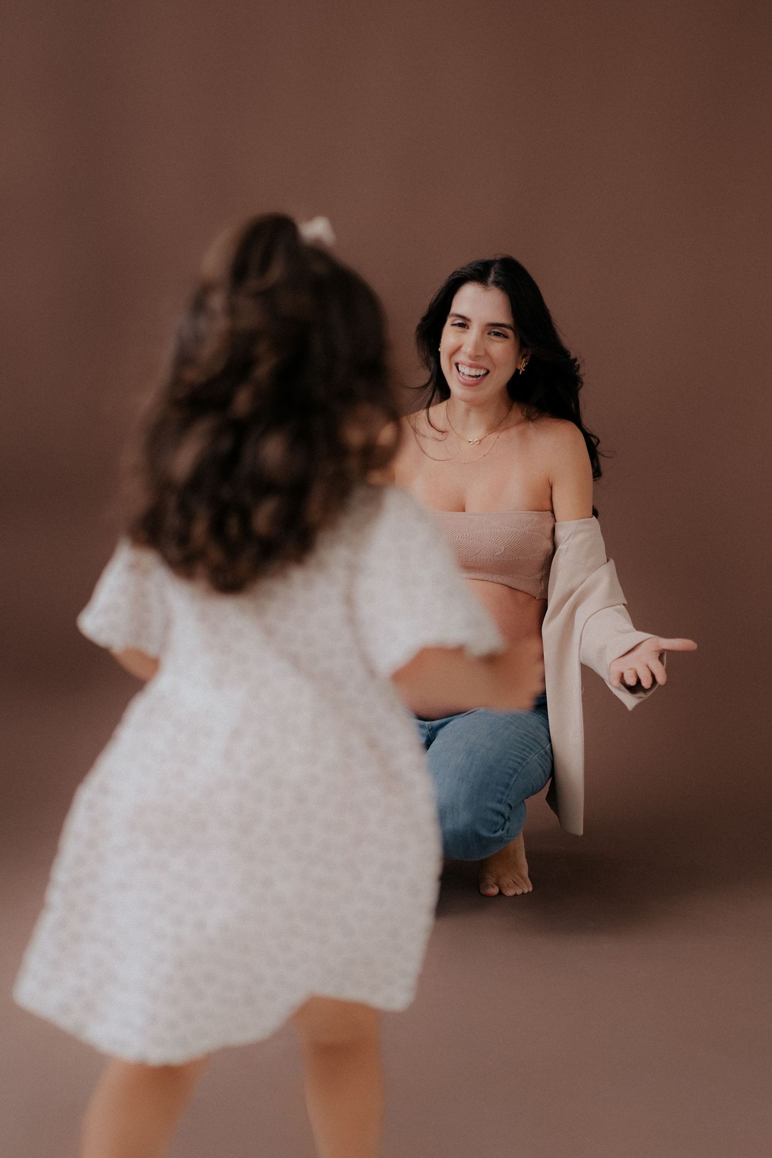 Joyful interaction between two people during indoor photoshoot against brown background.