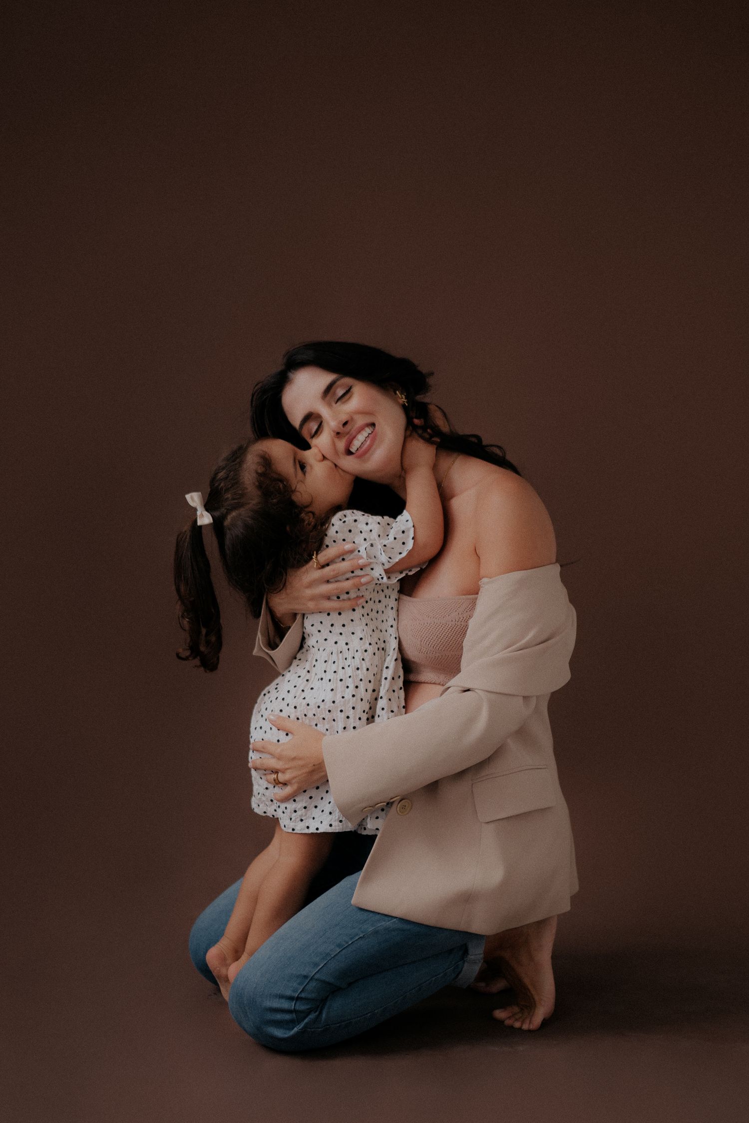 Candid moment of joy shared between parent and child during studio photoshoot.