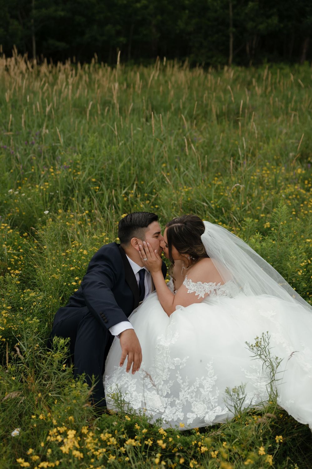 Newlyweds share an intimate moment lying in a wildflower meadow on their wedding day.