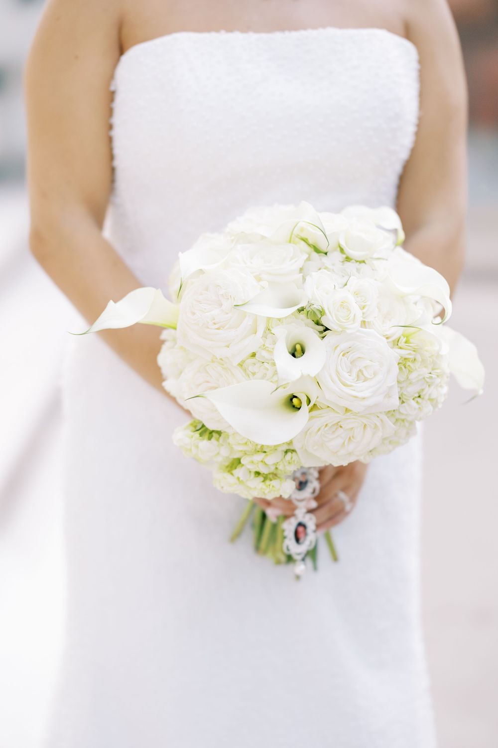 A series of white wedding bouquets held by a bride in a white dress against a light background.
