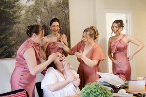 Wedding party in pink dresses getting ready in a bright indoor room.