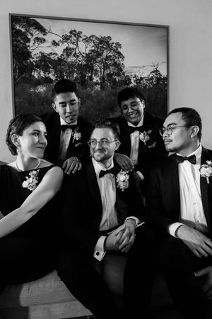 Black and white photo of groomsmen sharing laughs and embracing before the wedding.