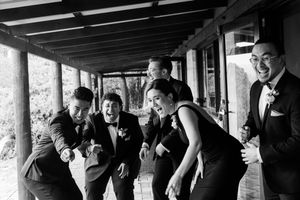 Black and white panoramic series of groomsmen laughing on a covered porch.