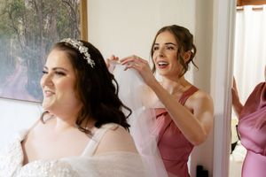 Getting ready on wedding morning in a light-filled room with rose-colored dresses and joyful preparations.