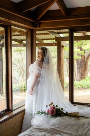 Sunlit bridal portraits in a wooden pavilion with flowing white dress and veil.