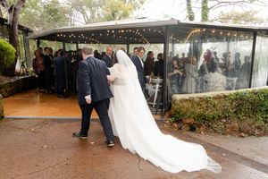 A bride and groom dance during their romantic autumn wedding celebration under an outdoor pavilion with string lights.
