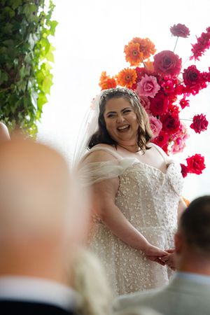 A close-up view of a beautiful wedding dress with sparkling beaded details and red floral decorations in the background.