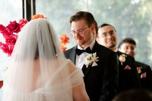 Wedding ceremony guests in formal attire watch attentively as bride and groom share their vows at the altar.