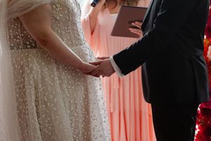 Close up view of wedding couple during first dance highlighted by pink and orange floral decor in background.
