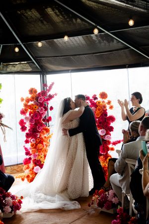 Sequence of wedding moments captured against vibrant red flower wall and natural lighting.