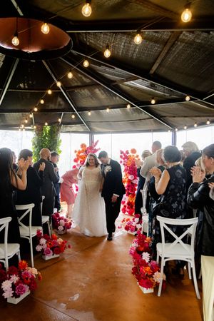 Wedding photography of the groom and bride walking down the isle with guests celebrating around them